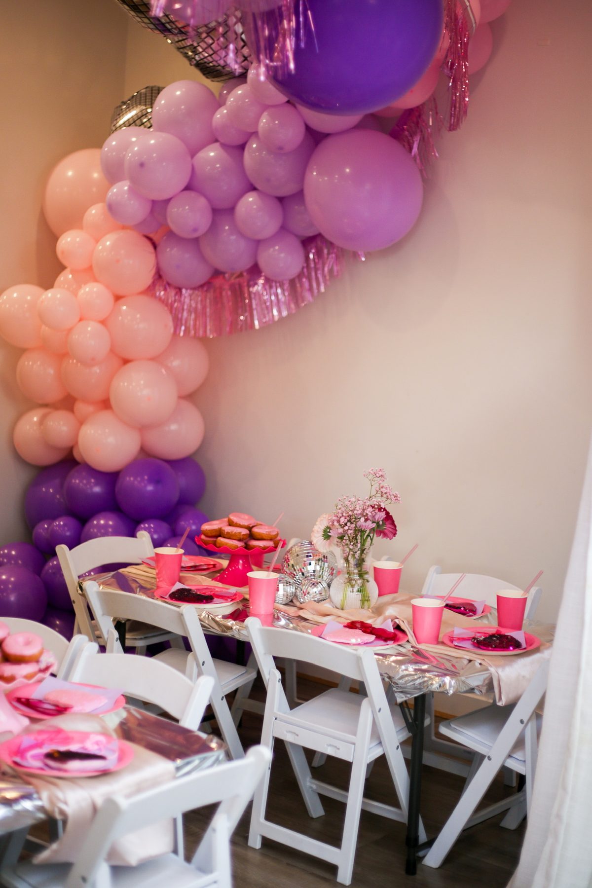 Pink and purple balloon styling behind a first birthday party table