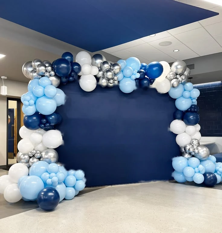 Blue, white and silver balloon arch around a navy backdrop